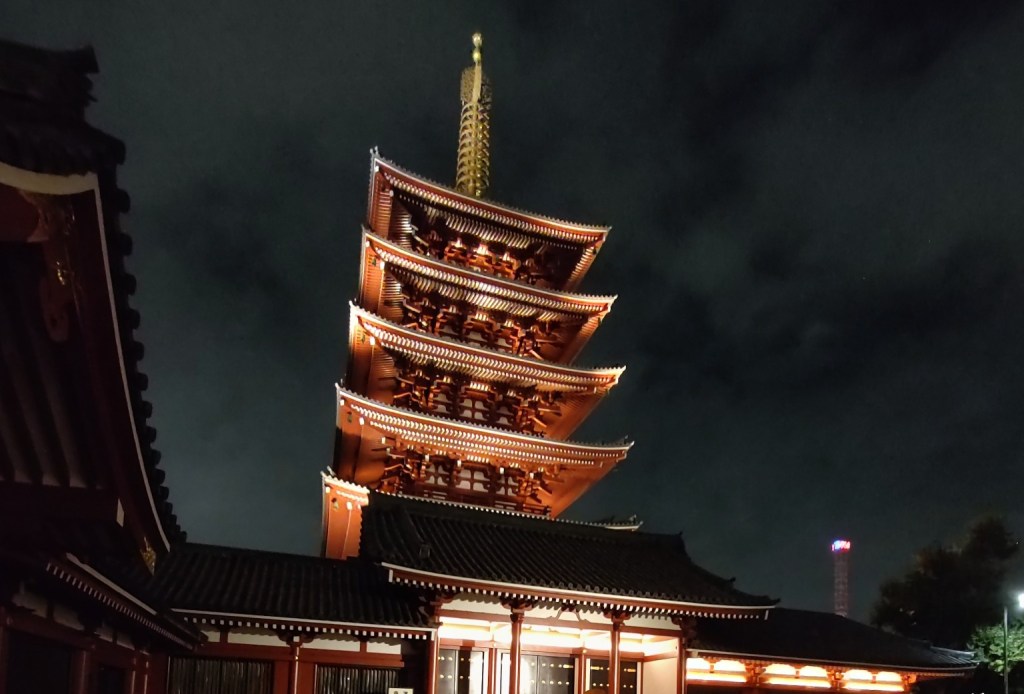 A traditional Japanese five-story pagoda illuminated against the night sky.